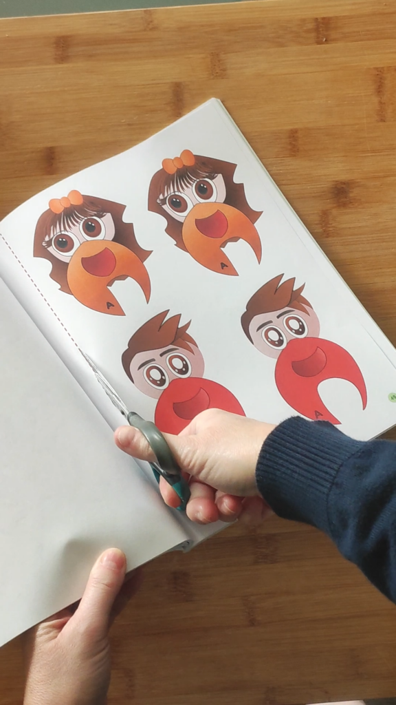 mano che ritaglia una pagina del libro "Stickeriamo l'alfabeto"